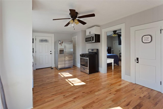 kitchen featuring light wood finished floors, baseboards, appliances with stainless steel finishes, and white cabinets