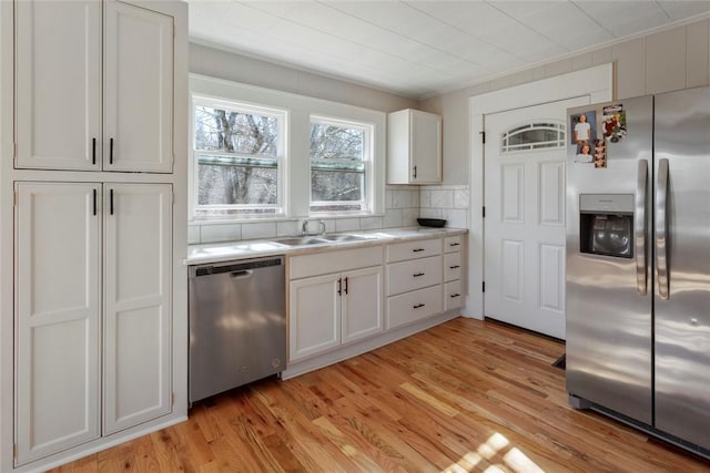 kitchen featuring light wood finished floors, light countertops, appliances with stainless steel finishes, white cabinets, and a sink