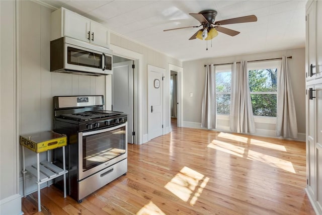 kitchen featuring light wood-style flooring, ornamental molding, gas stove, white cabinets, and ceiling fan