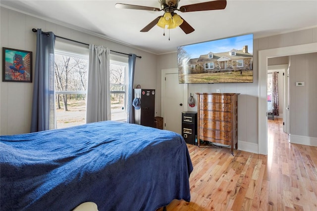 bedroom with light wood-style floors, crown molding, baseboards, and a ceiling fan