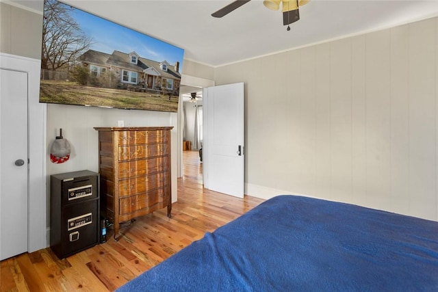 bedroom featuring light wood-style flooring, ornamental molding, and a ceiling fan