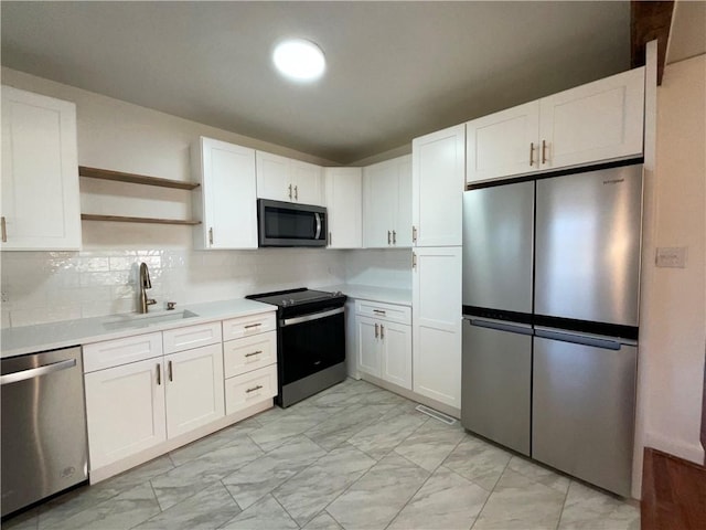 kitchen featuring marble finish floor, stainless steel appliances, light countertops, white cabinetry, and a sink