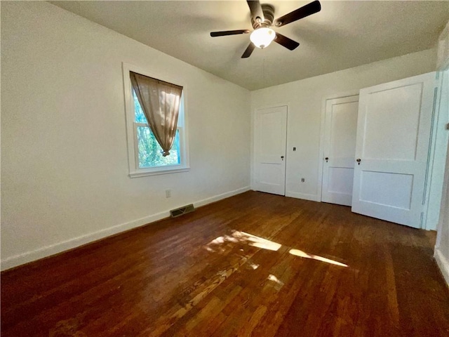 unfurnished bedroom with a ceiling fan, baseboards, visible vents, and wood finished floors