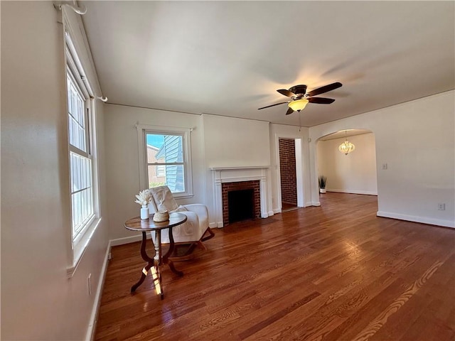1003 S Walnut St, Seneca, SC 29678 - living room featuring baseboards, wood finished floors, a ceiling fan, arched walkways, and a brick fireplace