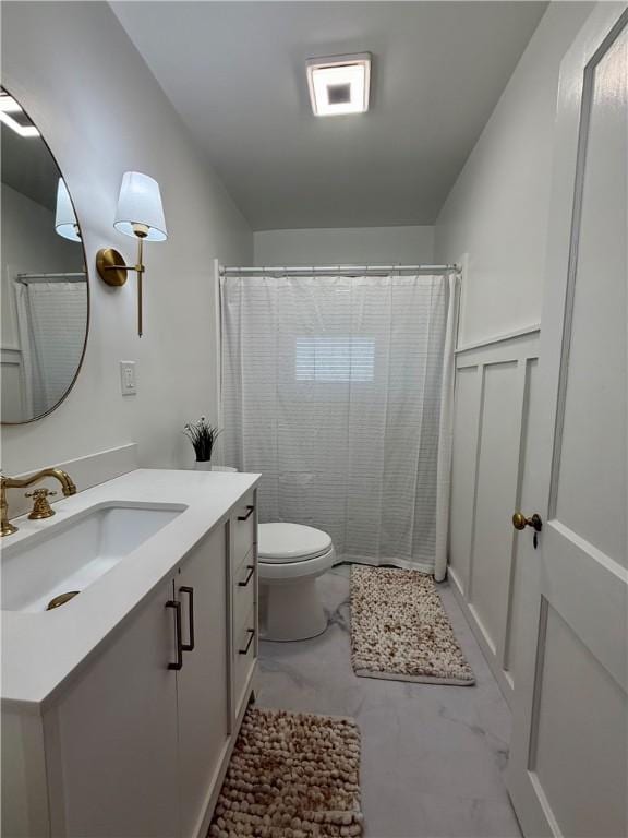 bathroom featuring a decorative wall, toilet, wainscoting, vanity, and a shower with curtain