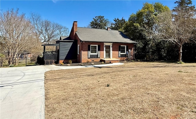 view of front of house with crawl space, brick siding, a chimney, and a front lawn