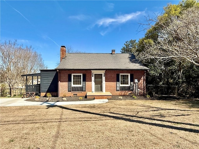 view of front facade with brick siding, fence, roof with shingles, crawl space, and a chimney