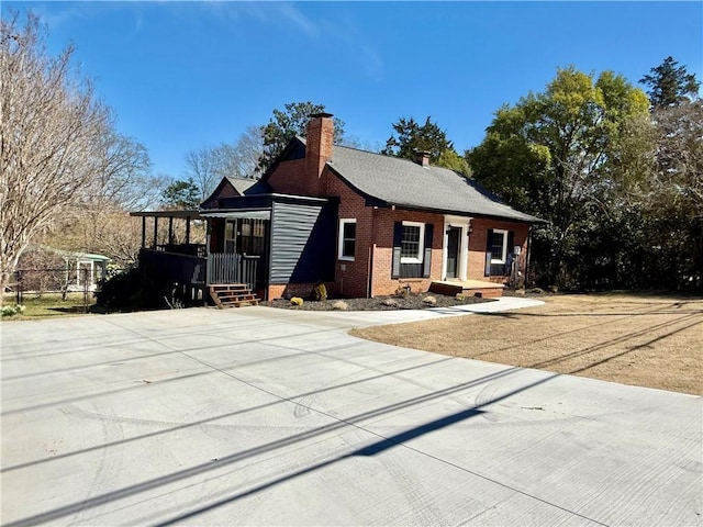 view of front of home with a chimney and brick siding