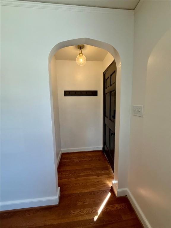 corridor featuring arched walkways, wood finished floors, and baseboards