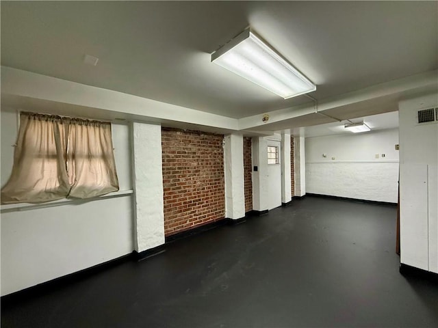 finished basement with visible vents and brick wall