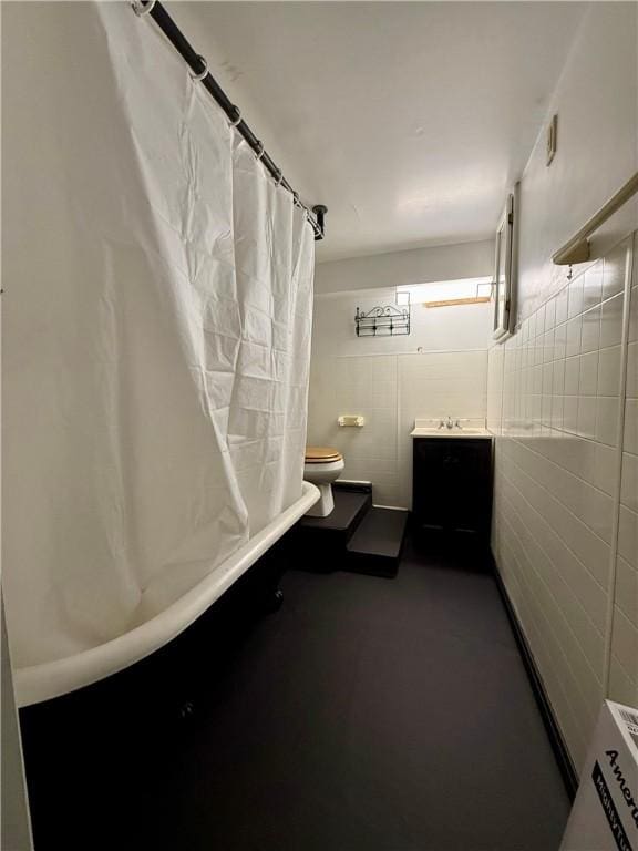 bathroom with shower / tub combo, vanity, toilet, and tile walls