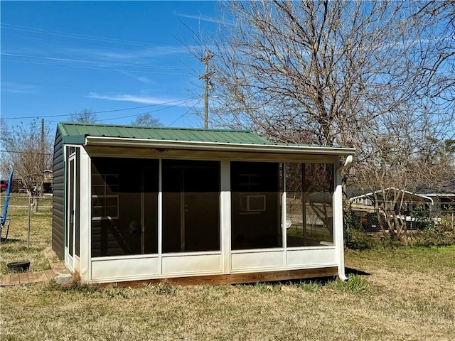 view of outbuilding with fence and a sunroom