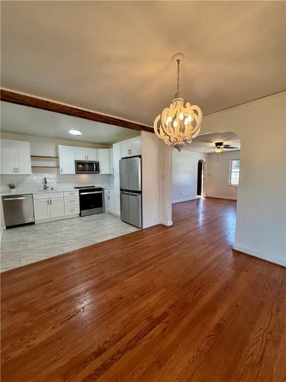 kitchen with arched walkways, stainless steel appliances, open floor plan, and white cabinetry