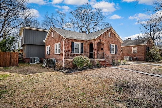 view of front of property featuring brick siding, central AC unit, and fence