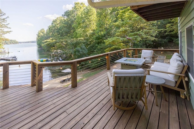 wooden deck featuring an outdoor fire pit and a water view