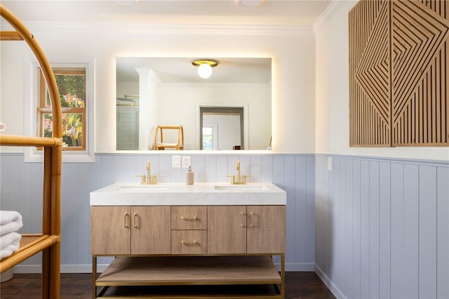 bathroom with double vanity, wood finished floors, a sink, and crown molding