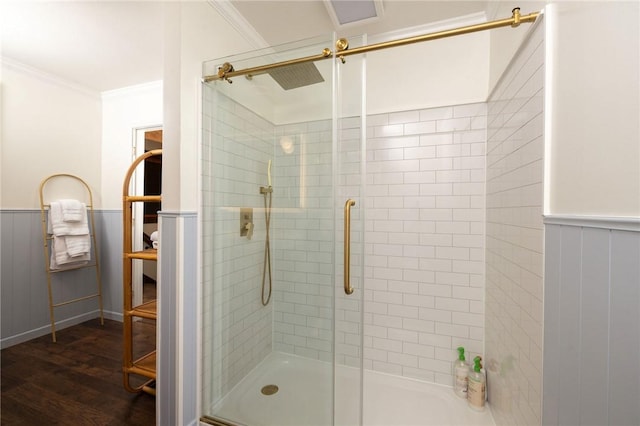 bathroom featuring wood finished floors, wainscoting, a shower stall, and crown molding