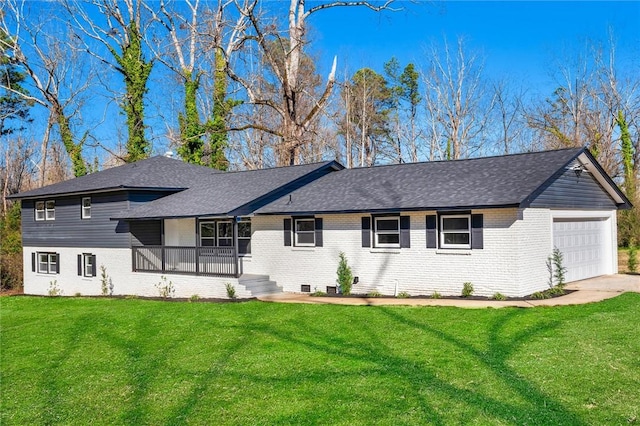 rear view of property with a garage, roof with shingles, brick siding, and a lawn