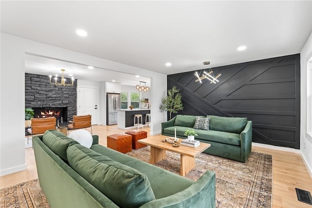 living area featuring visible vents, an accent wall, light wood-style floors, a fireplace, and recessed lighting