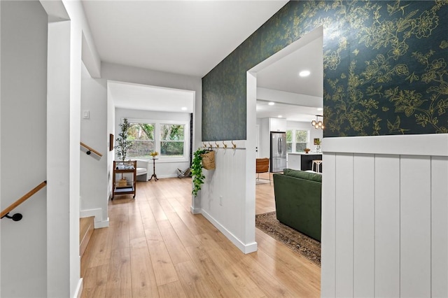 hall with light wood finished floors, plenty of natural light, and wallpapered walls