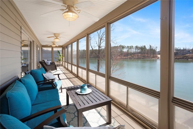 sunroom / solarium with a ceiling fan and a water view