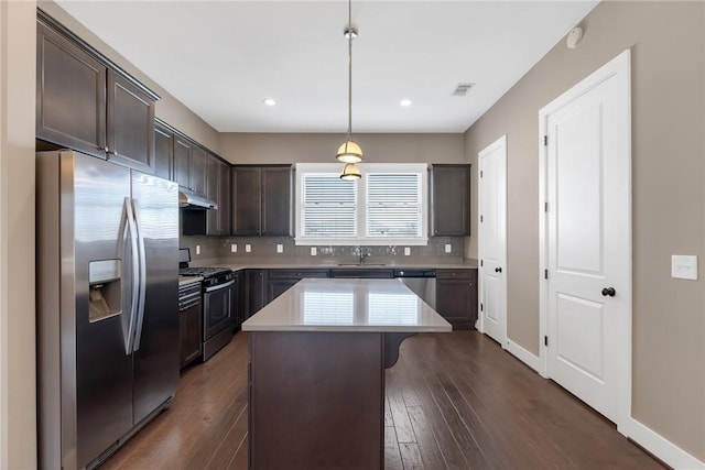 kitchen with a breakfast bar area, dark brown cabinetry, stainless steel appliances, a sink, and tasteful backsplash