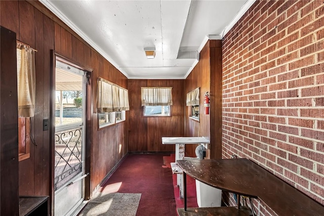 interior space with crown molding, wood walls, and brick wall