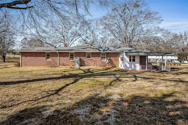 rear view of property featuring crawl space, brick siding, a yard, and a chimney