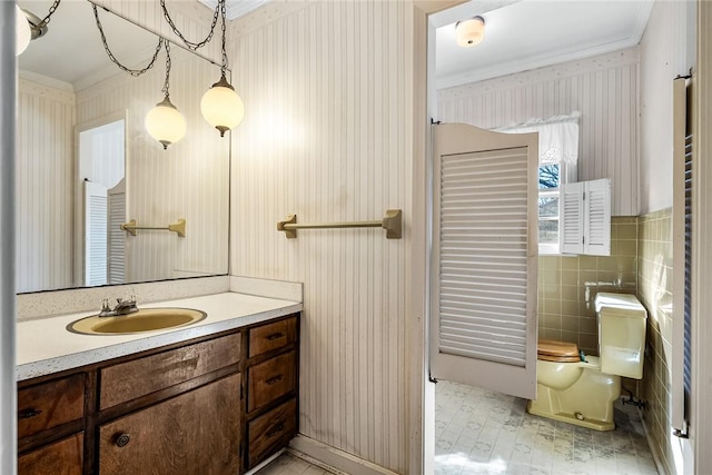 bathroom featuring tile walls, vanity, toilet, and crown molding