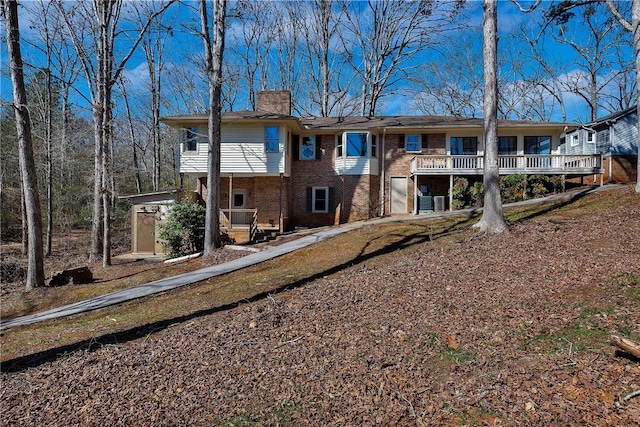 rear view of property featuring an outbuilding, brick siding, and a chimney