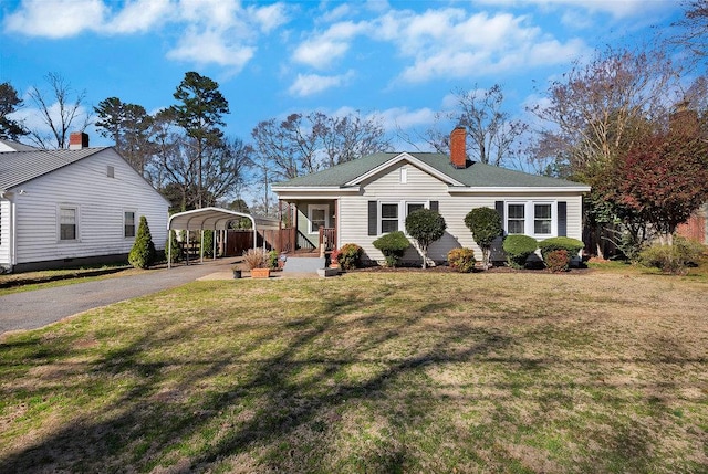 view of front of house with a chimney, a front lawn, aphalt driveway, and a carport