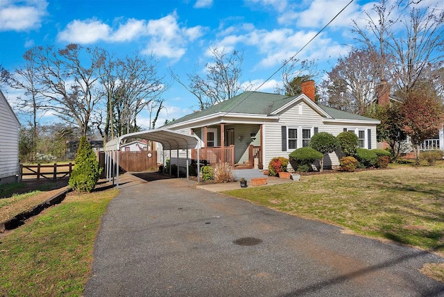 bungalow with aphalt driveway, a chimney, fence, a carport, and a front lawn