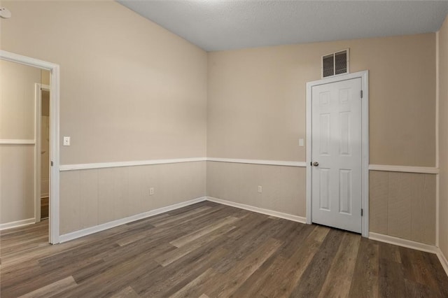 unfurnished room with wainscoting, visible vents, a textured ceiling, and wood finished floors