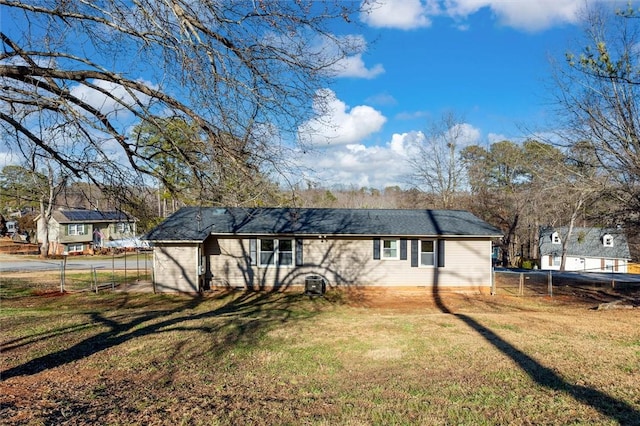 rear view of property featuring a lawn and fence