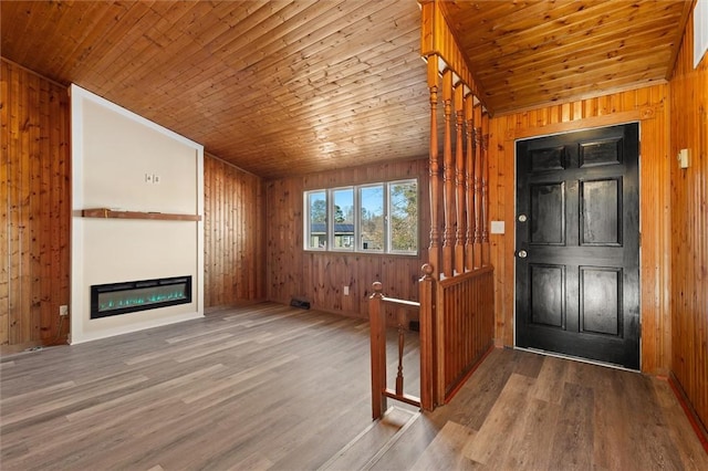 entryway with wood finished floors, a glass covered fireplace, and wood ceiling