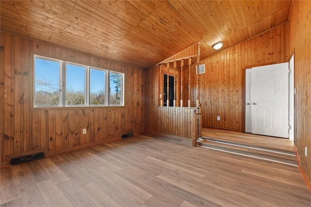 spare room featuring lofted ceiling, wooden ceiling, wood finished floors, and wood walls