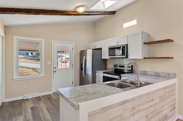 kitchen with open shelves, appliances with stainless steel finishes, lofted ceiling with skylight, and visible vents