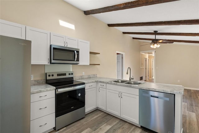 kitchen featuring open shelves, stainless steel appliances, light countertops, a sink, and a peninsula