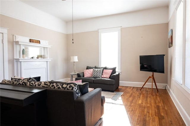 living area with a fireplace, baseboards, and wood finished floors