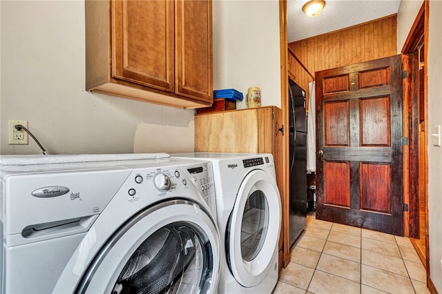 laundry room featuring light tile patterned floors, a textured ceiling, washing machine and dryer, and cabinet space