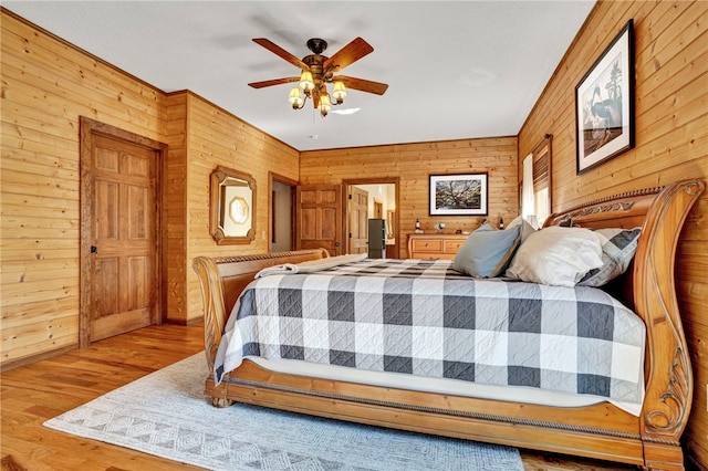 bedroom with wood walls, ceiling fan, and wood finished floors