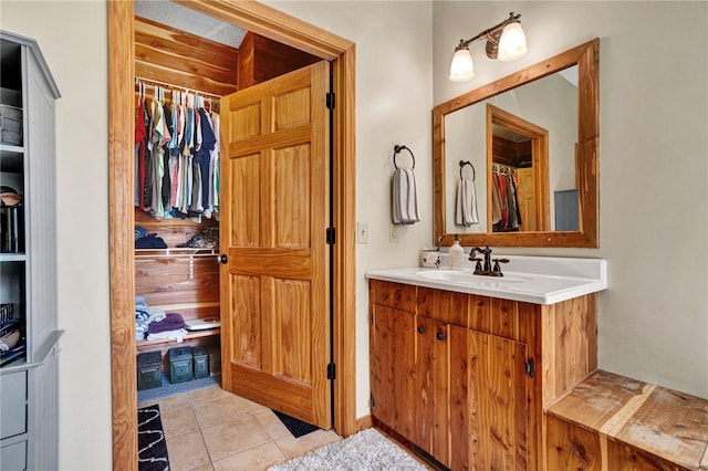 bathroom with tile patterned flooring, a spacious closet, and vanity