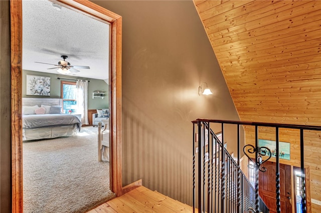 stairway with carpet, a ceiling fan, a textured ceiling, and wood finished floors