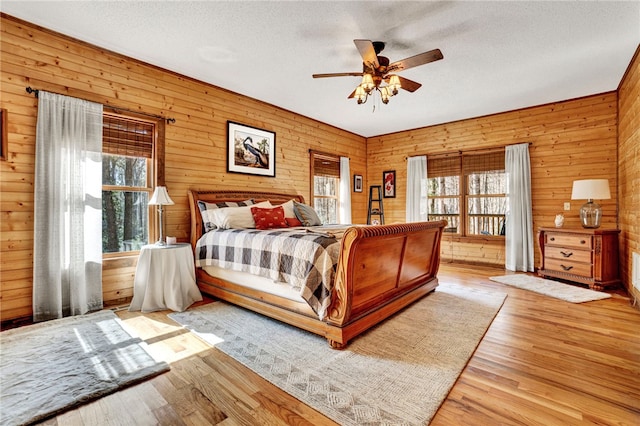 bedroom featuring wooden walls, a textured ceiling, and wood finished floors