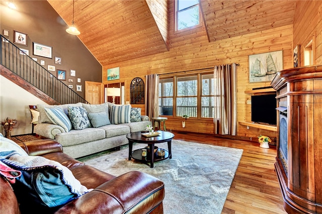 living room featuring wooden walls, wooden ceiling, stairway, wood finished floors, and high vaulted ceiling