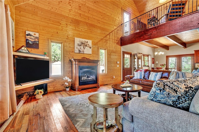 living room with a glass covered fireplace, beam ceiling, wood walls, and hardwood / wood-style floors