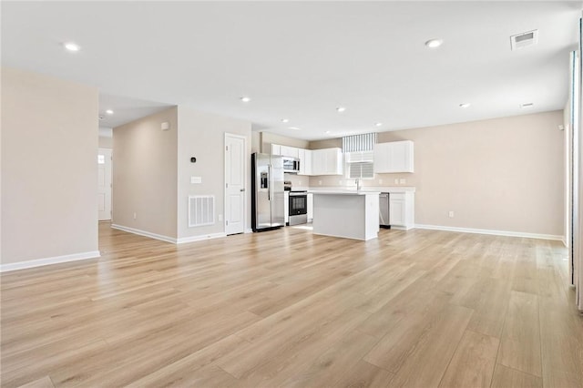 unfurnished living room with light wood-style floors, recessed lighting, visible vents, and baseboards