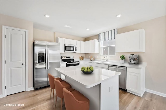 kitchen with stainless steel appliances, a center island, white cabinetry, and a sink