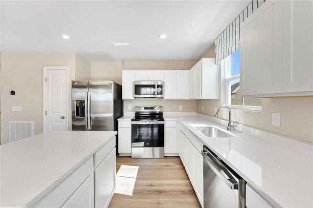 kitchen with visible vents, appliances with stainless steel finishes, light countertops, light wood-type flooring, and a sink