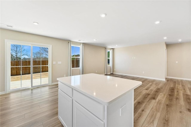 kitchen with a center island, recessed lighting, light countertops, light wood-style flooring, and white cabinets